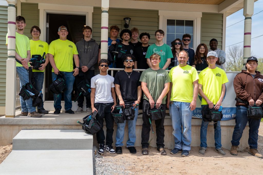 Bridges Construction & Renovation program students pose during a graduation ceremony at the completed build.